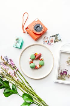 Beautiful background with dessert, polaroid camera and flowers. Top view on white table