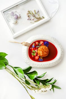 Dessert fried ice cream in strawberry sauce with berries. Top view with copy space on white table