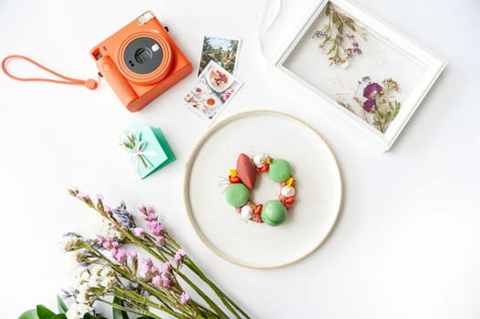 Beautiful background with dessert, polaroid camera and flowers. Top view on white table