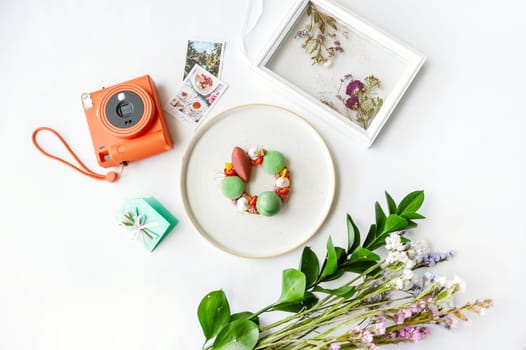 Beautiful background with dessert, polaroid camera and flowers. Top view on white table