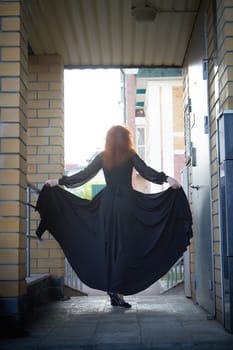 Elegant Woman Twirling in Black Dress on Staircase. Woman in a twirling black dress captured mid-movement on the porch of the house