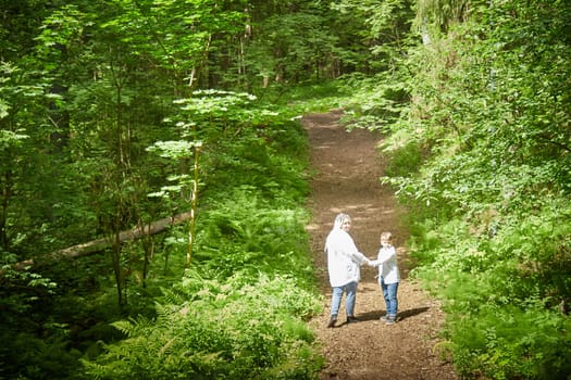 Funny mother with dreadlocks and fat boy happy walking in the forest on a sunny summer day