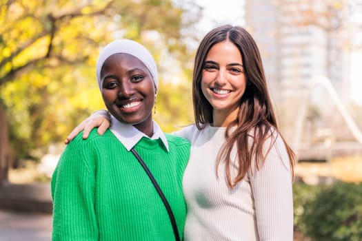 multiracial couple of two young women smiling looking at camera, concept of friendship and happiness