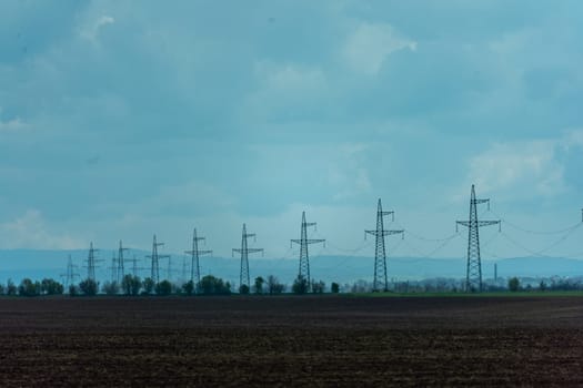 High voltage towers with sky background. Power line support with wires for electricity transmission. High voltage grid tower with wire cable at distribution station. Energy industry, energy saving.