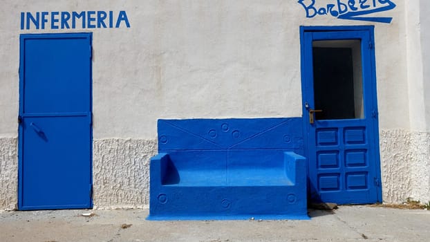 Asinara, Italy. August 11, 2021. Entrance to the infirmary and the barber shop with waiting sofa, of the prison museum on the hill of the island.