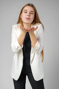 Young Woman Blowing Kiss While Wearing a White Blazer and Black Top close up