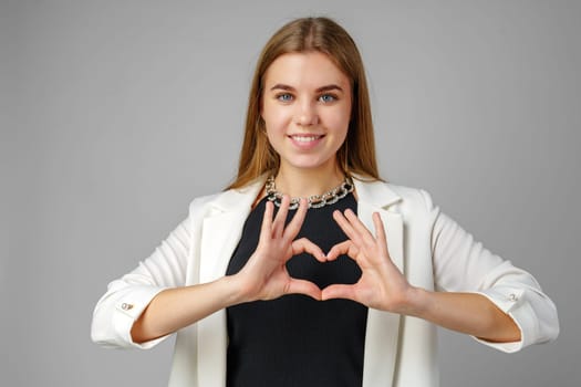 Woman Making Heart With Hands on gray background in studio
