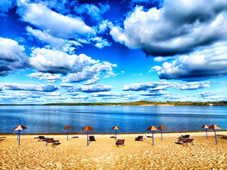 Beach, umbrellas, water and sky with clouds on sunny day. Tourism, vacations, recreation