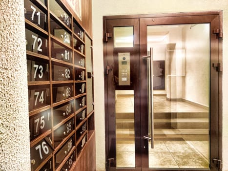 Mailboxes in hallway or entrance. Hallway featuring numbered mailboxes next to glass doors. Residential Building Entrance With Modern Mailboxes