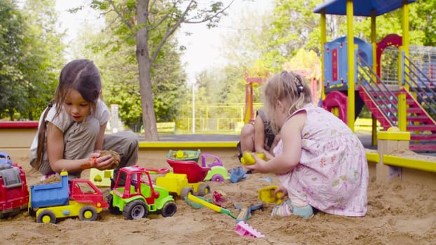 Two girls sitting in a sandbox and playing in the sand