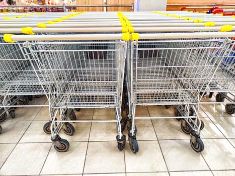 Grocery baskets on wheels in the store. Row of Metal Shopping Baskets on Wheels Inside a Grocery Store. Metal shopping carts lined up at a grocery