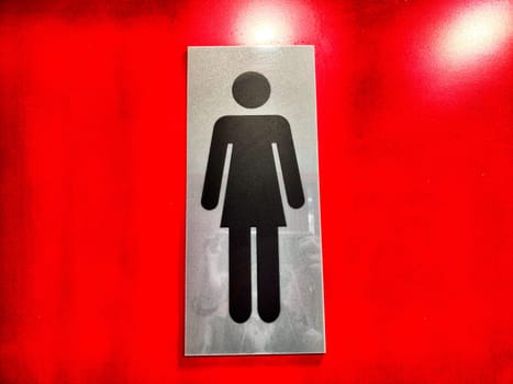 Womens Restroom Sign on a Red Background. A sign indicating a womens restroom against vibrant red wall