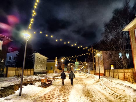 Arkhangelsk, Russia - February 28, 2024: street at night in winter. Snowy, cobblestone street adorned with lights