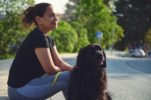 Authentic side portrait of a beautiful young adult woman and her black cocker spaniel dog while walking it on leash. Playing pets. The concept of love, care and empathy for domestic animals