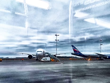 Moscow, Russia - April 04, 2024: planes at the airport, view through the window. Planes awaiting departure at dawn seen from an airplane window
