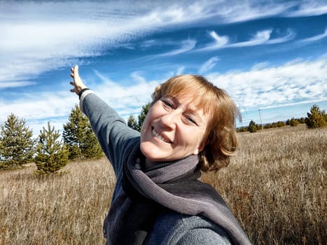 Happy female blonde tourist taking selfie picture outside. Middle aged mature woman having fun on an adventure trip on nature