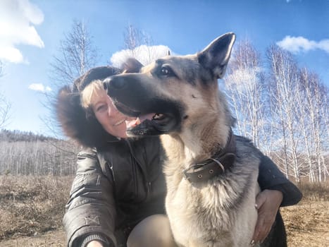 Adult girl or middle aged woman with shepherd dog in an autumn day