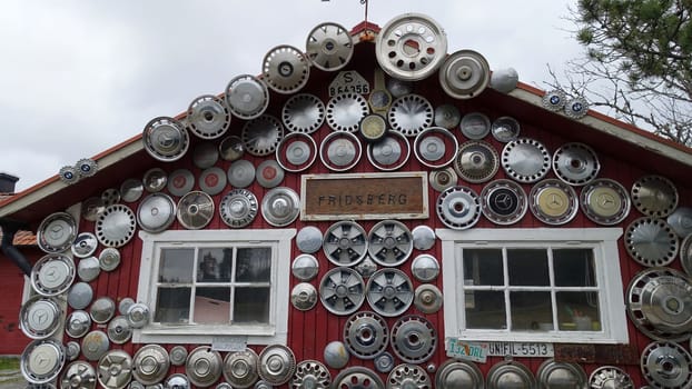 Sweden, April 21, 2024. The facade of a house dotted with antique car rims. View from the street during a cloudy day.