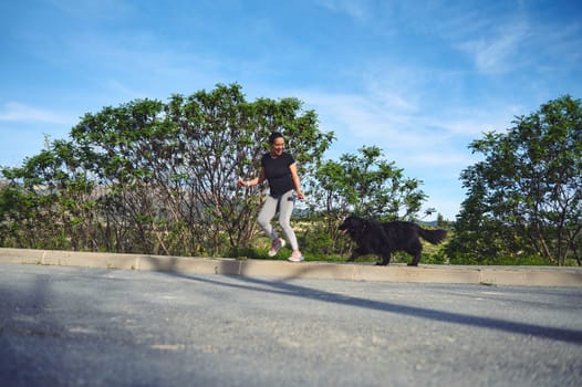 Cheerful woman running with her pet on leash, as perfect way to walk a dog and to exercise outdoors. People. Animals. Nature. Active and healthy lifestyle concept. Playing pets concept