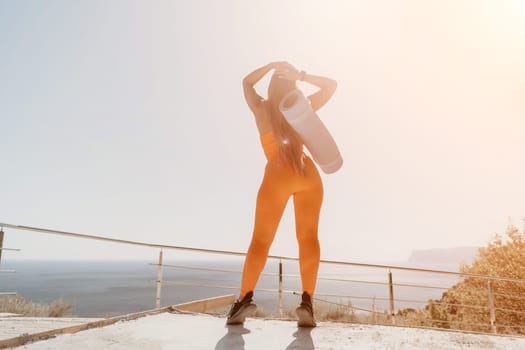 Fitness woman sea. Outdoor workout on yoga mat in park near to ocean beach. Female fitness pilates yoga routine concept. Healthy lifestyle. Happy fit woman exercising with rubber band in park.