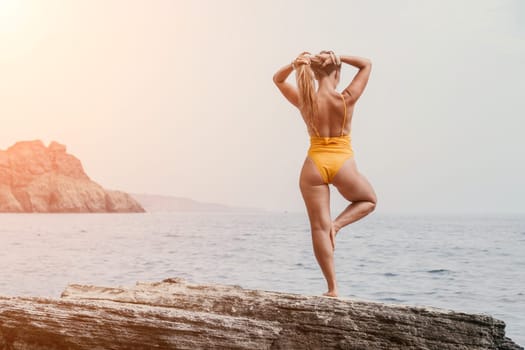 Woman meditating in yoga pose silhouette at the ocean, beach and rock mountains. Motivation and inspirational fit and exercising. Healthy lifestyle outdoors in nature, fitness concept.