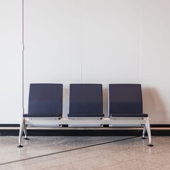 A row of chairs in a waiting room with a white wall behind them creating a sleek and modern environment