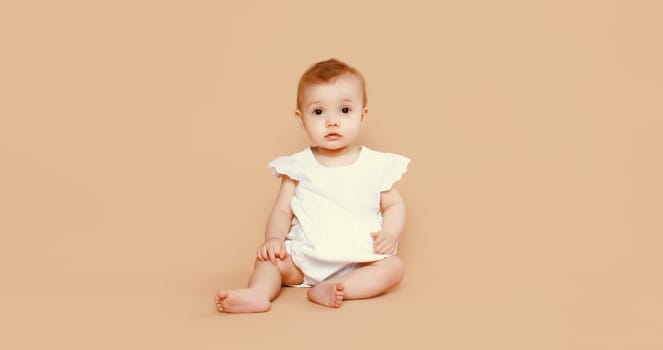 Portrait of happy cute baby crawling on the floor on brown studio background