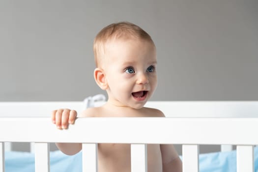 Close-up of a baby's face looking out of a crib with interest.