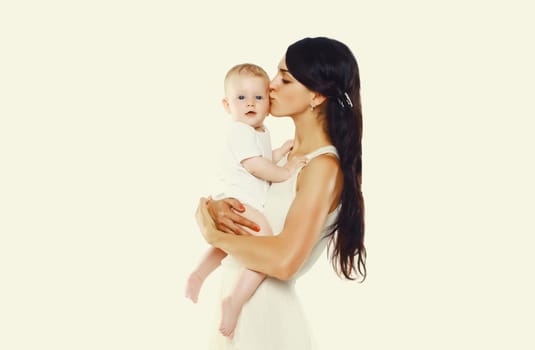 Happy young mother holding and kissing baby on white studio background