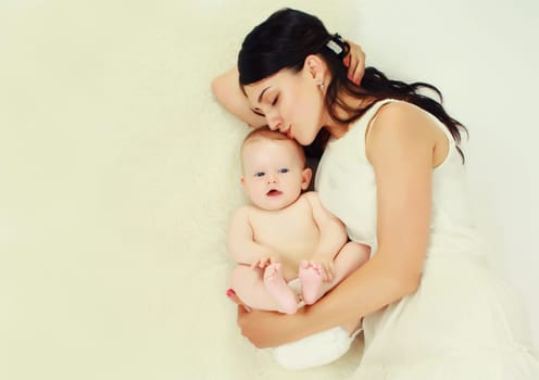 happy young mother lying with baby together on the floor at home