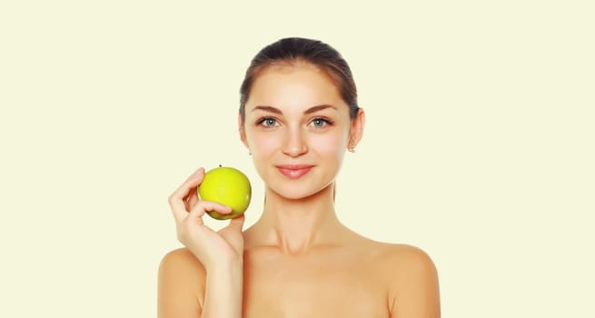 Beauty portrait of brunette smiling young woman holding fresh green apple on white studio background