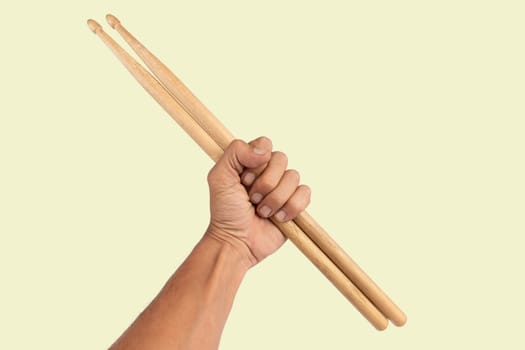 Black male hand holding wooden Drum sticks isolated on green background. High quality photo