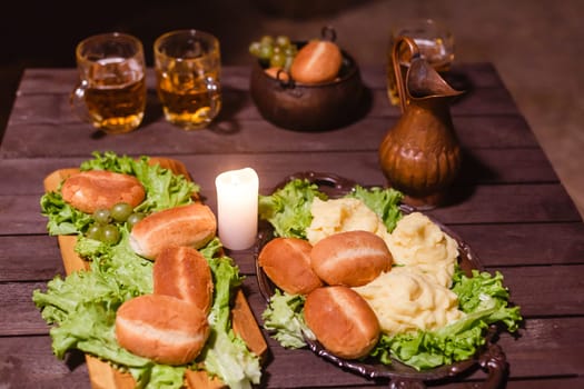 A glass of beer next to a candle on a table.