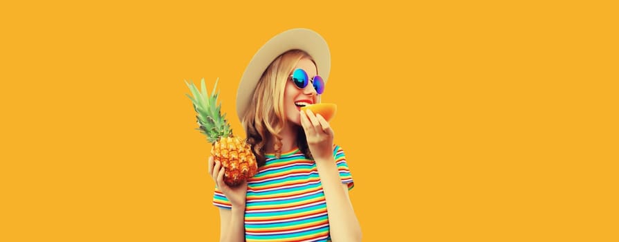 Summer portrait of happy smiling young woman with pineapple fruit in straw tourist hat, sunglasses on yellow studio background