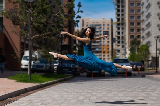 Beautiful Asian ballerina dancing outdoors. Urban landscape. Grand jete