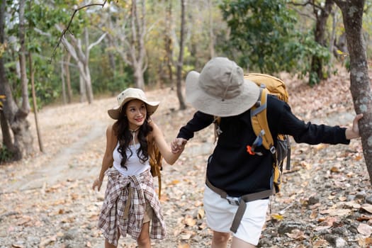 Happy LGBT Lesbian couple Travelers Hiking with Backpacks in waterfall Trail. LGBT Lesbian Couple Hikers with backpacks walks in mountains in vacation.