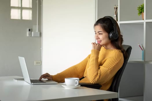 Beautiful young asian woman enjoy listening to music with headphone at desk home, happiness and relaxation concepts.