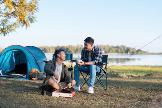 couple gay lgbt sitting in camp cooking and near river in mountains. Camping couple lgbt concept.
