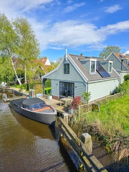 A lone boat peacefully bobs in the tranquil waters, the stillness of the scene contrasted by the subtle ripples around it. wooden facades and old houses in Broek in Waterland in the Netherlands