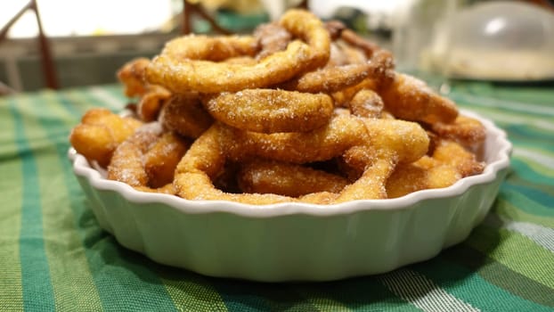 A tray of fried dough snakes with sugar ready to eat. Traditional Italian Frittelle.