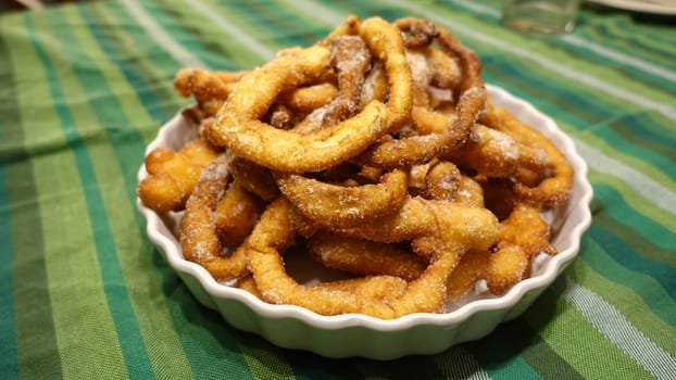A tray of fried dough snakes with sugar ready to eat. Traditional Italian Frittelle.