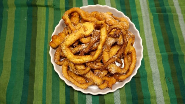 A tray of fried dough snakes with sugar ready to eat. Traditional Italian Frittelle.