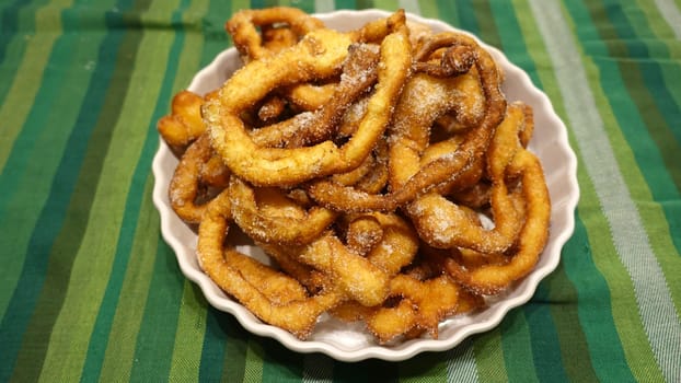 A tray of fried dough snakes with sugar ready to eat. Traditional Italian Frittelle.