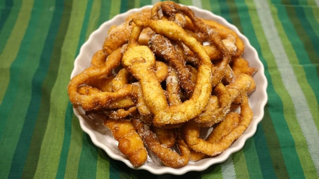 A tray of fried dough snakes with sugar ready to eat. Traditional Italian Frittelle.