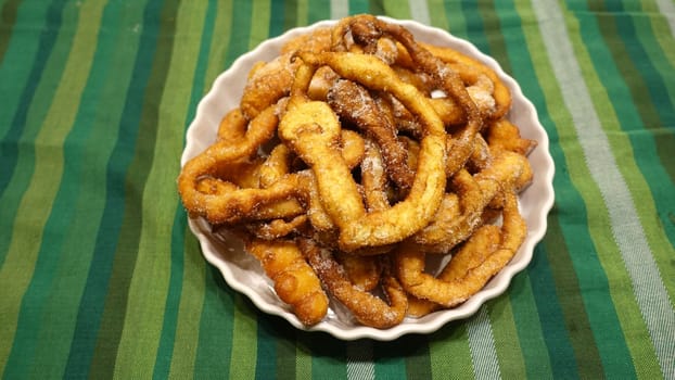 A tray of fried dough snakes with sugar ready to eat. Traditional Italian Frittelle.