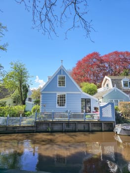 A picturesque blue house stands peacefully next to a tranquil body of water, creating a serene and idyllic scene. Broek in Waterland Netherlands