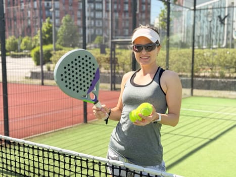 Portrait of active emotional woman playing padel tennis on open court in summer, swinging racket to return ball over net .. High quality photo