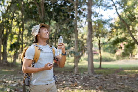 Traveler hiking man carrying a backpack on the back and walking in national park. man asian is rest by drink water.