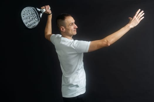 Paddle tennis player ready for serve on gray background. High quality photo