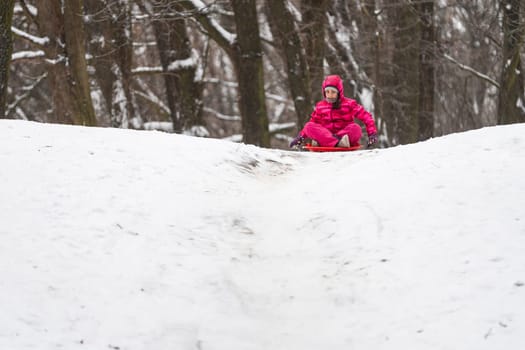 Girl enjoying a sleigh ride, play outdoors in snow. High quality photo